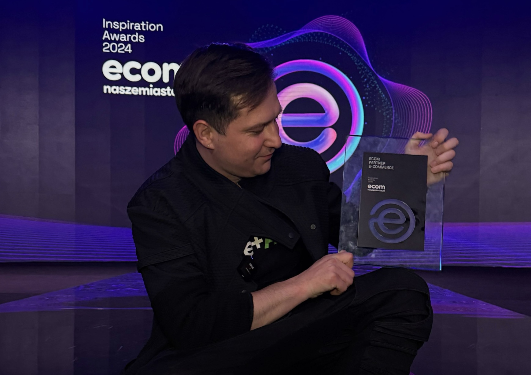 Aureliusz Gorski receiving ECOM Inspiration Awards 2024 special award on stage with clear acrylic plaque